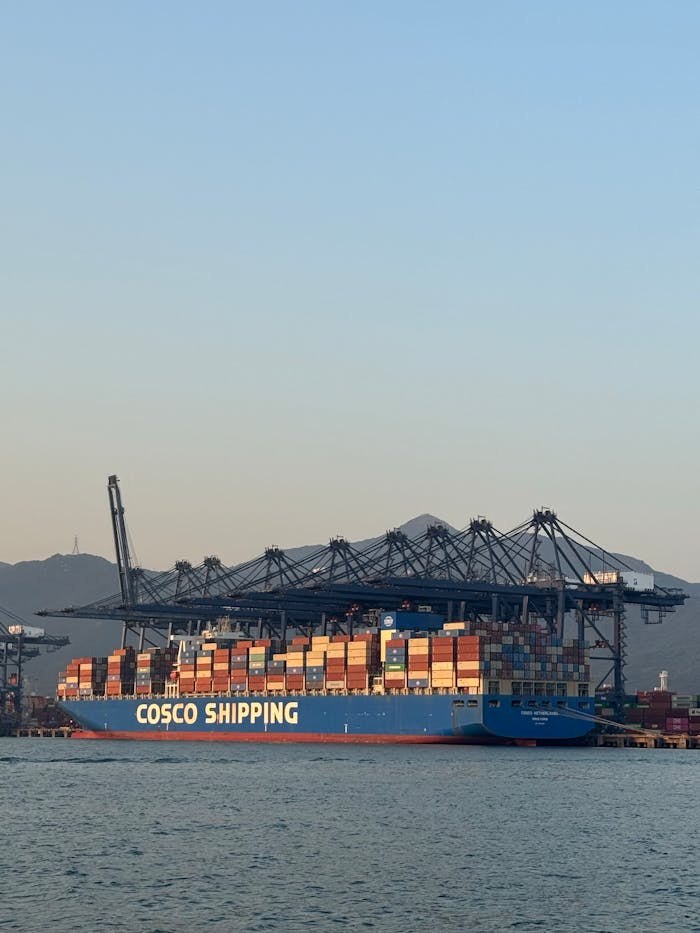 COSCO Shipping cargo ship loaded with containers at a busy port.